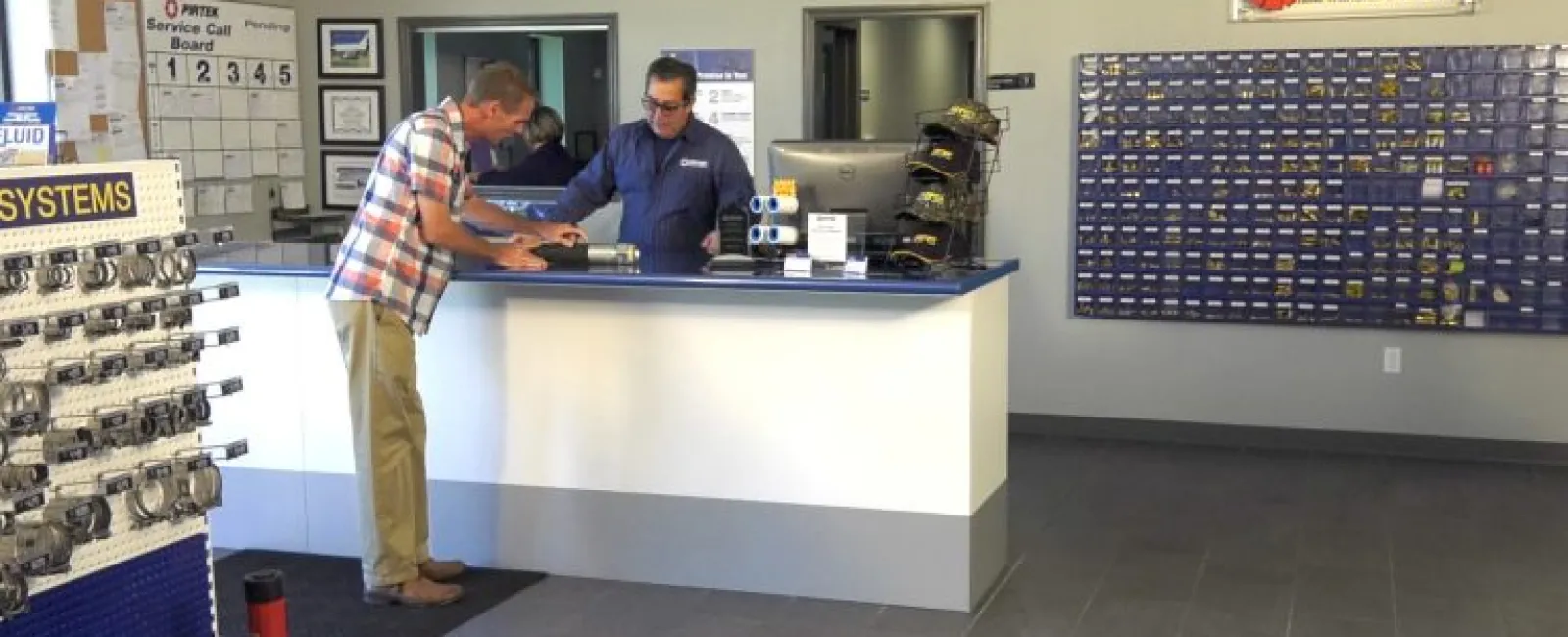 Customer at service counter assisted by store employee in a hydraulic parts and service shop interior.