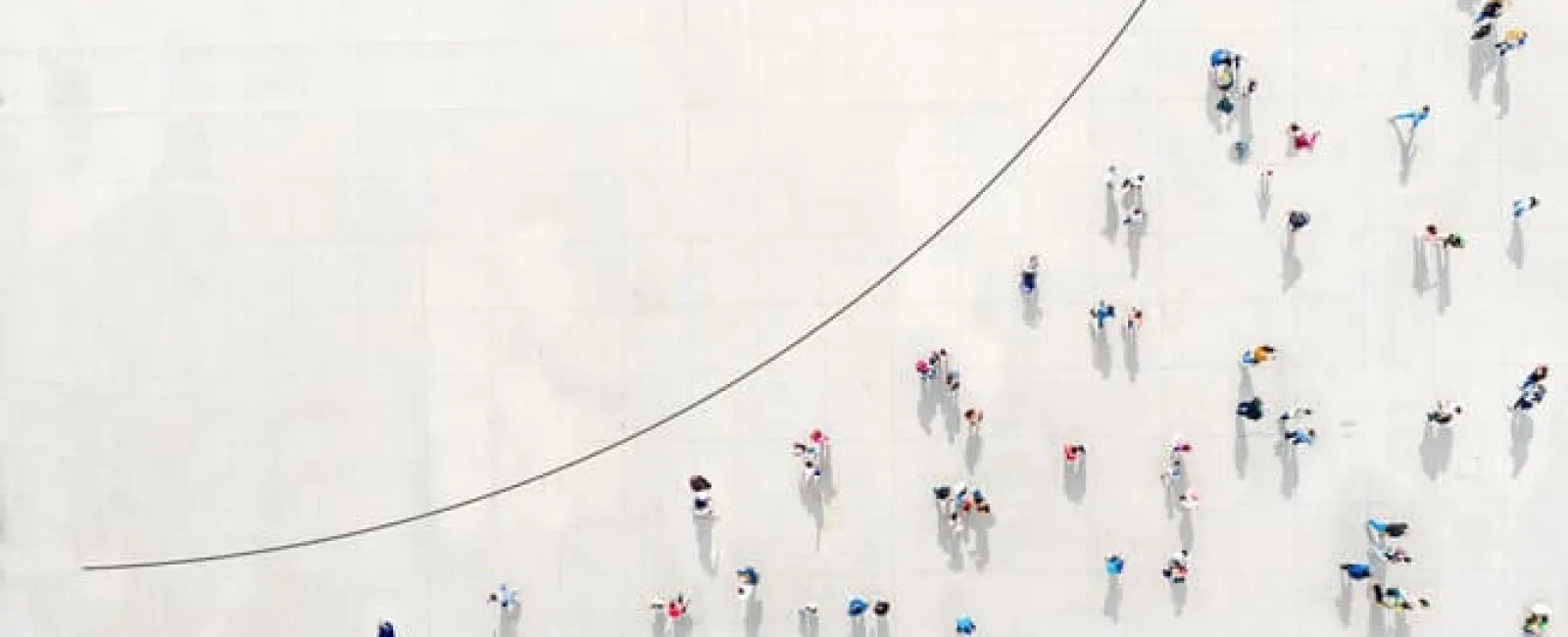 Aerial view of people walking along an upward trending arrow symbolizing growth and progress.