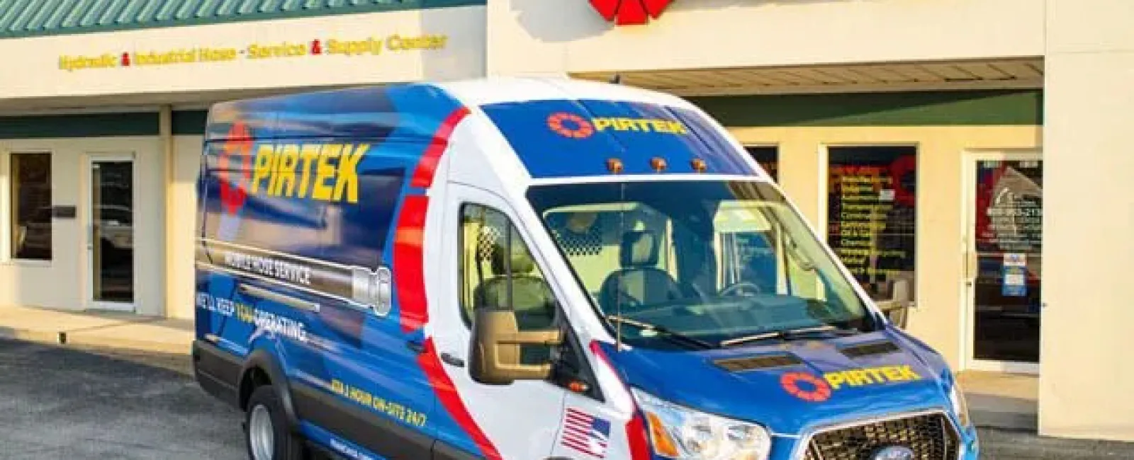 Pirtek service van parked outside a Pirtek hydraulic and industrial hose service center building.
