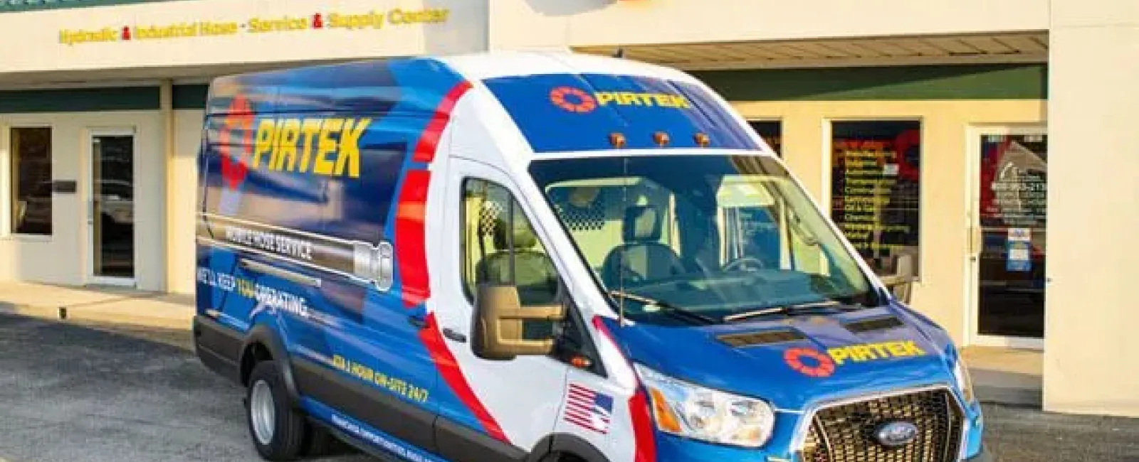 Pirtek service van parked outside a Pirtek hydraulic and industrial hose service center building.
