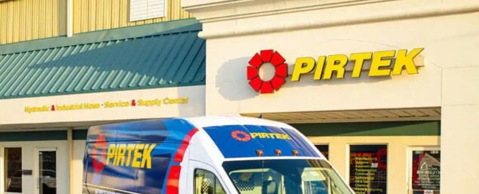 Pirtek service van parked outside a Pirtek hydraulic and industrial hose service center building.