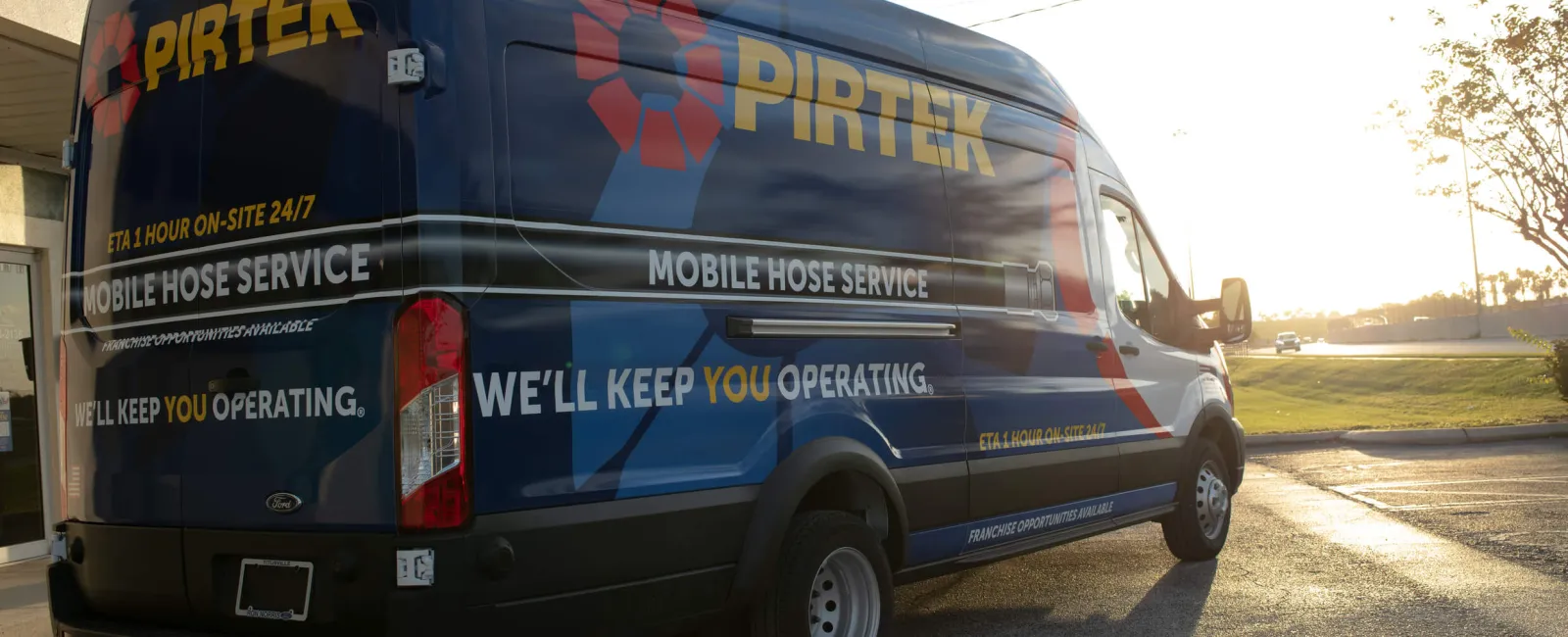 Blue PIRTEK mobile hose service van parked outside at sunset with company branding and slogan visible.