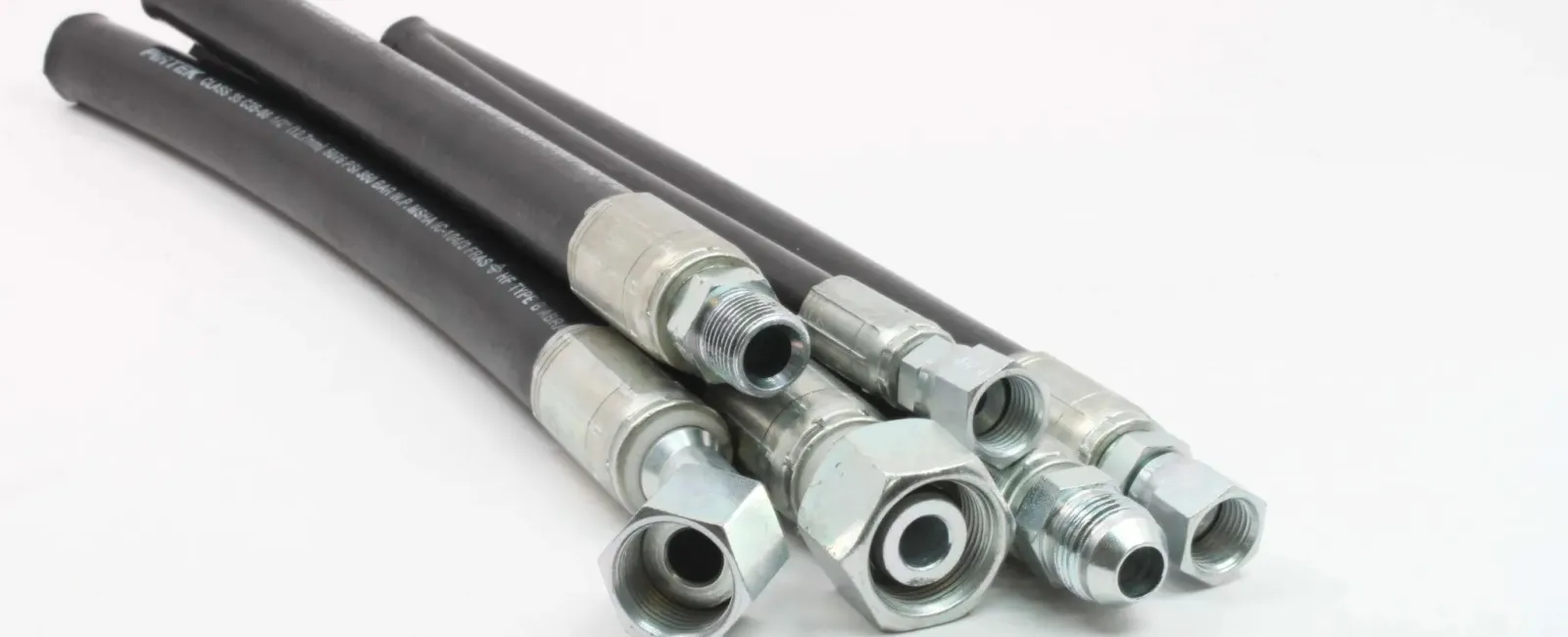 Set of black hydraulic hoses with silver metal fittings on white background