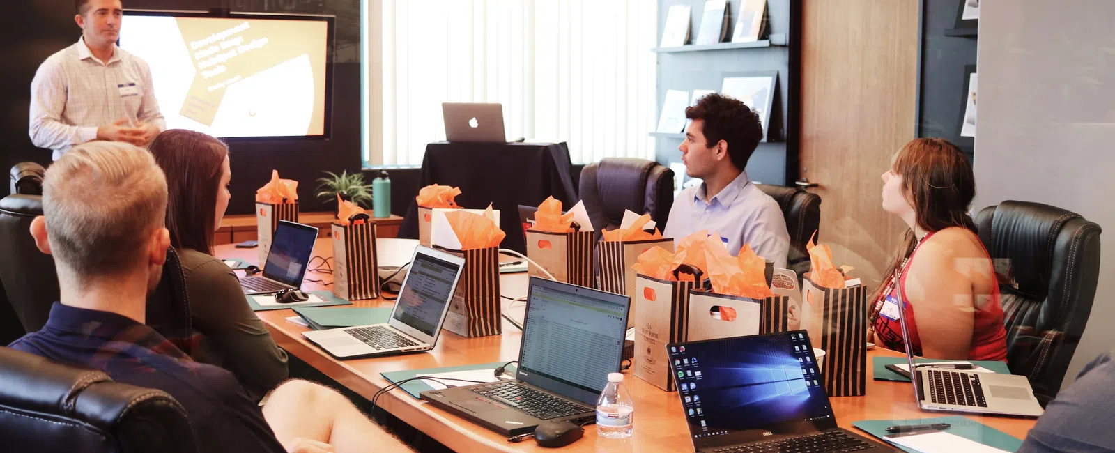 a group of people sitting around a table with laptops