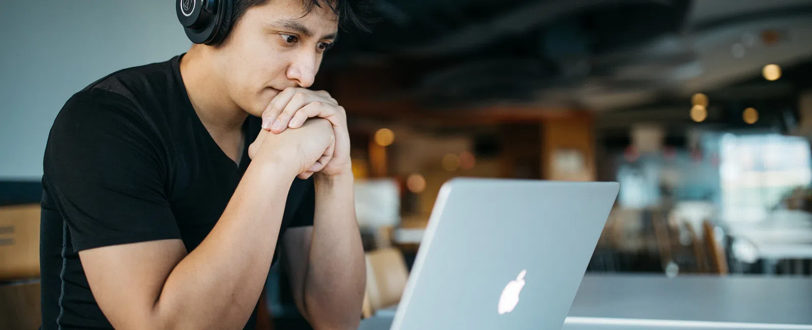 a person wearing headphones and sitting at a table with a laptop