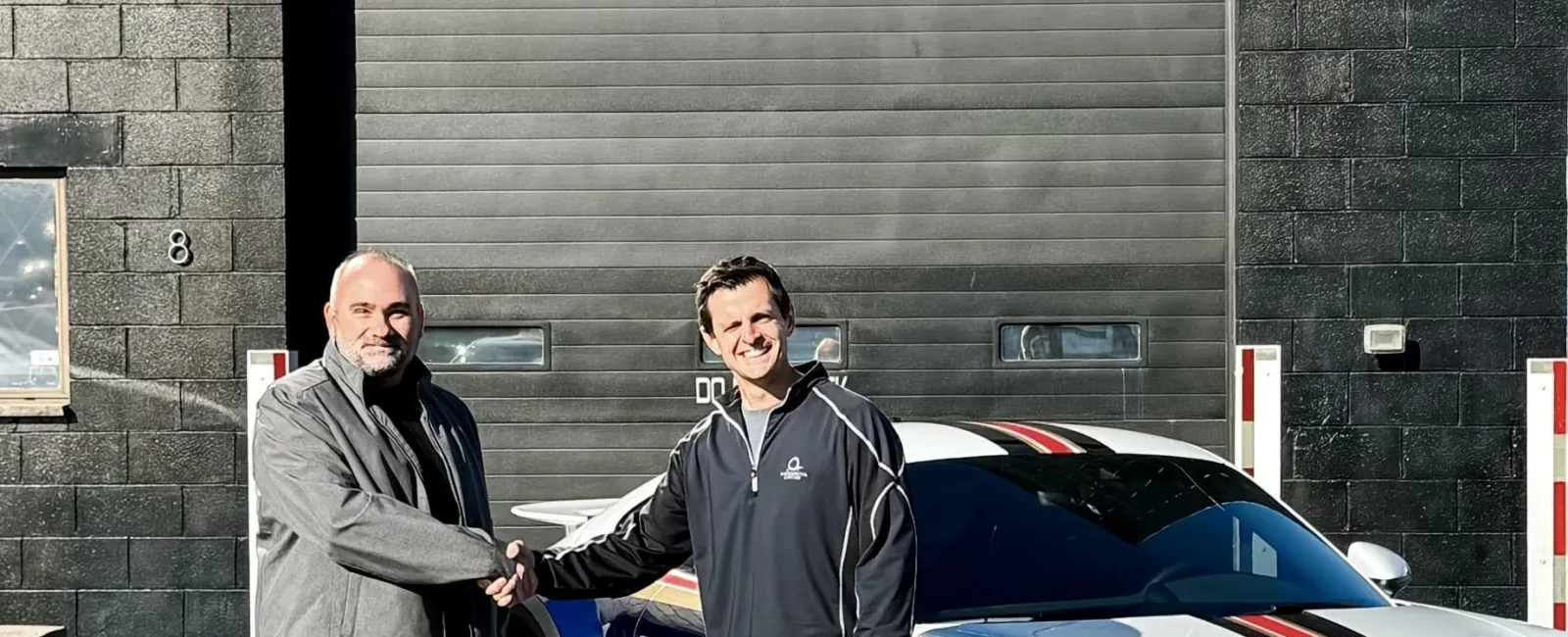 two men standing next to a car