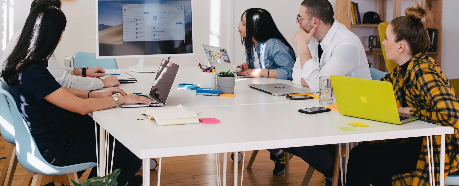 a group of people sitting around a table with laptops