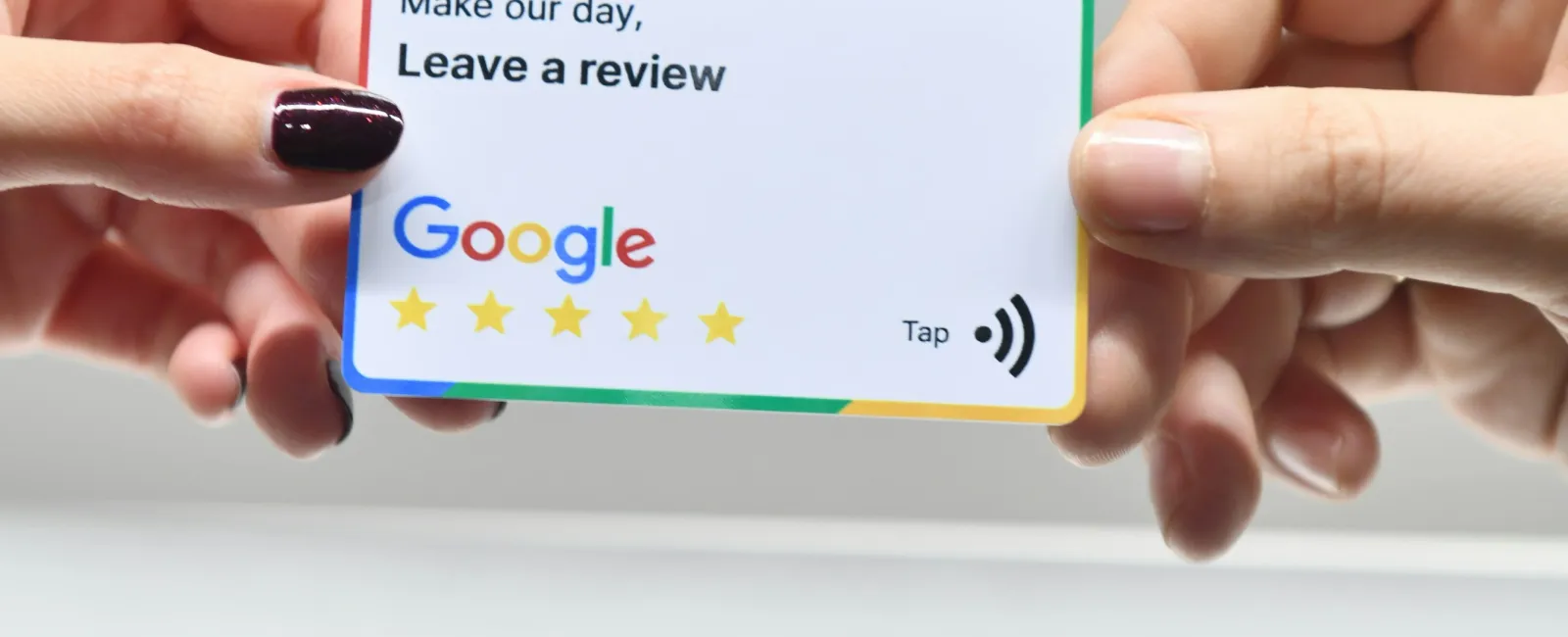 Two hands holding a Google review card asking to leave a 5-star review with an Apple logo in background.