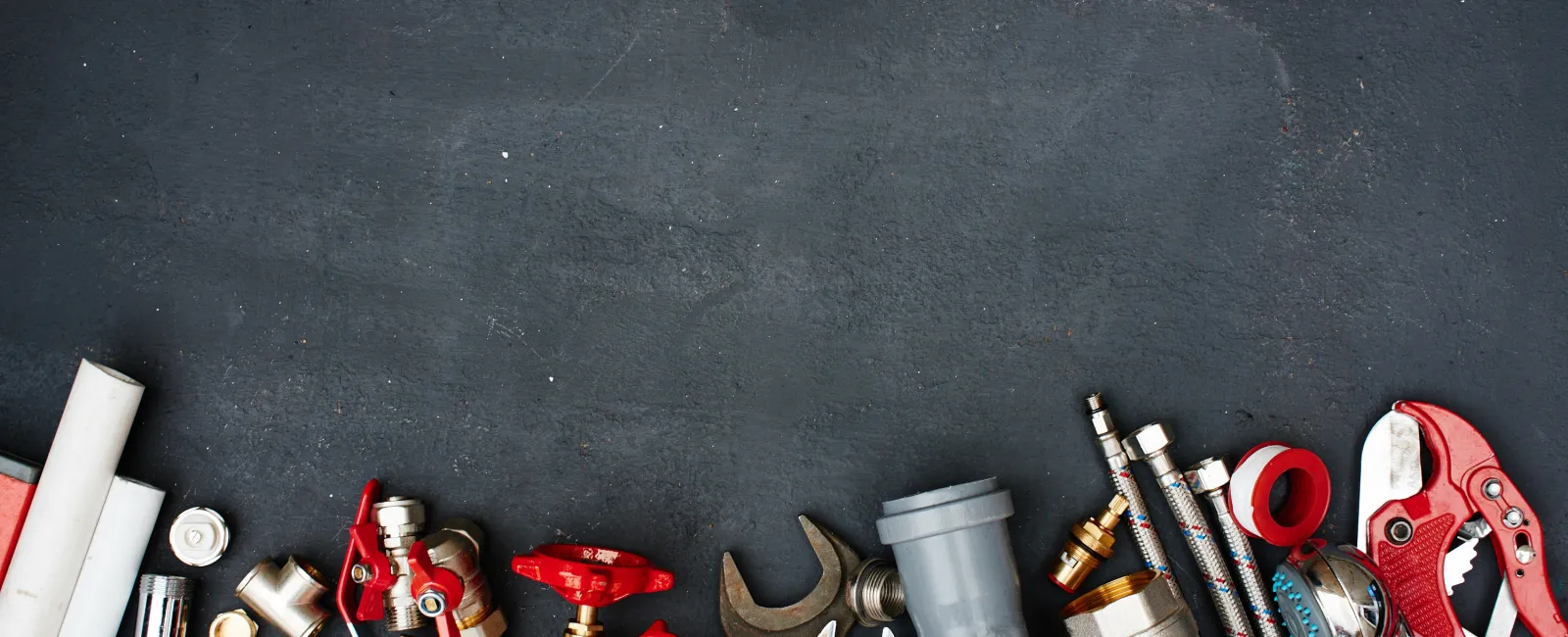 Variety of plumbing tools and fittings neatly arranged on a dark surface, ideal for DIY projects.