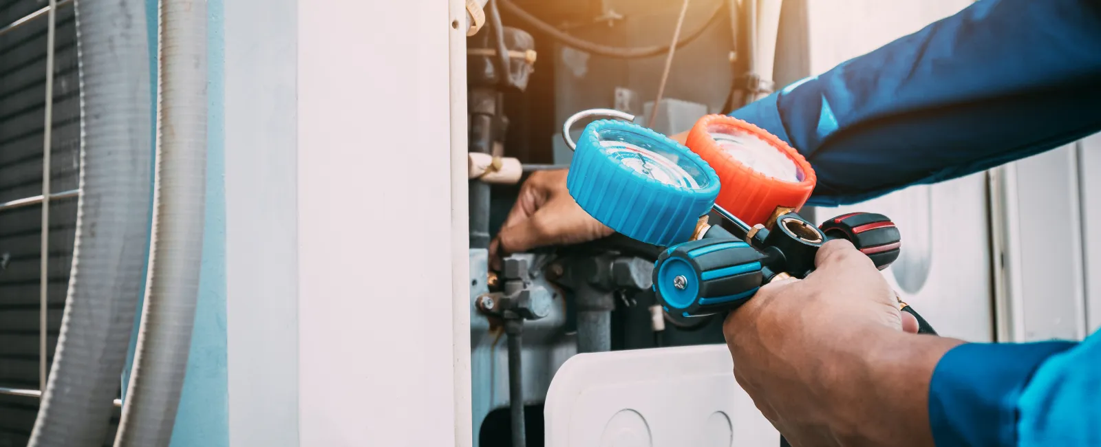 Technician using HVAC gauges to check air conditioning system pressure during maintenance work
