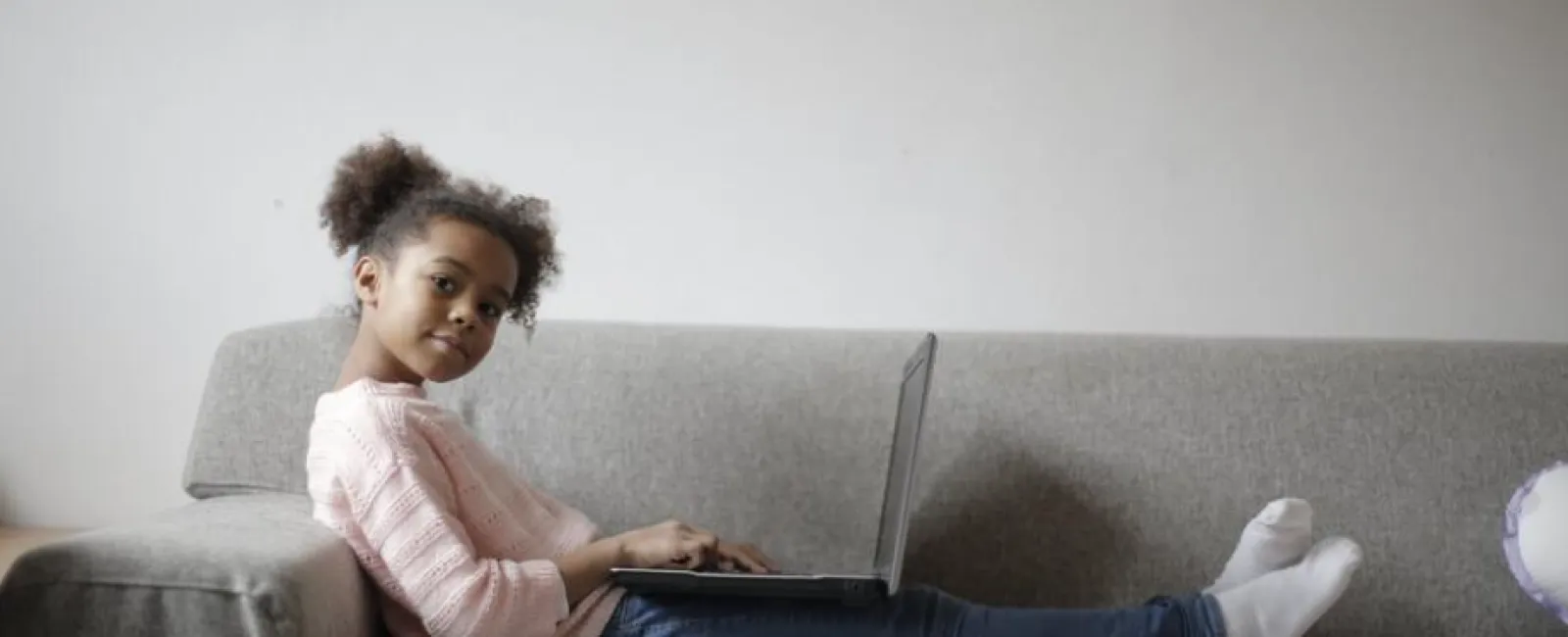 a girl sitting on a couch using a laptop