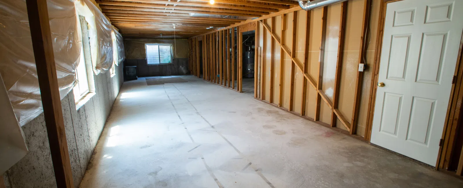 Spacious unfinished basement with bare walls, exposed beams, and concrete flooring, ready for renovation.