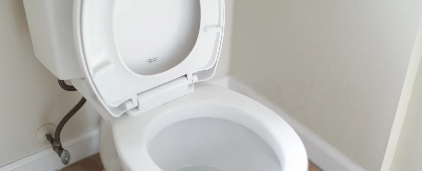 Clean white toilet in a modern bathroom setting with beige tiles and neutral walls.