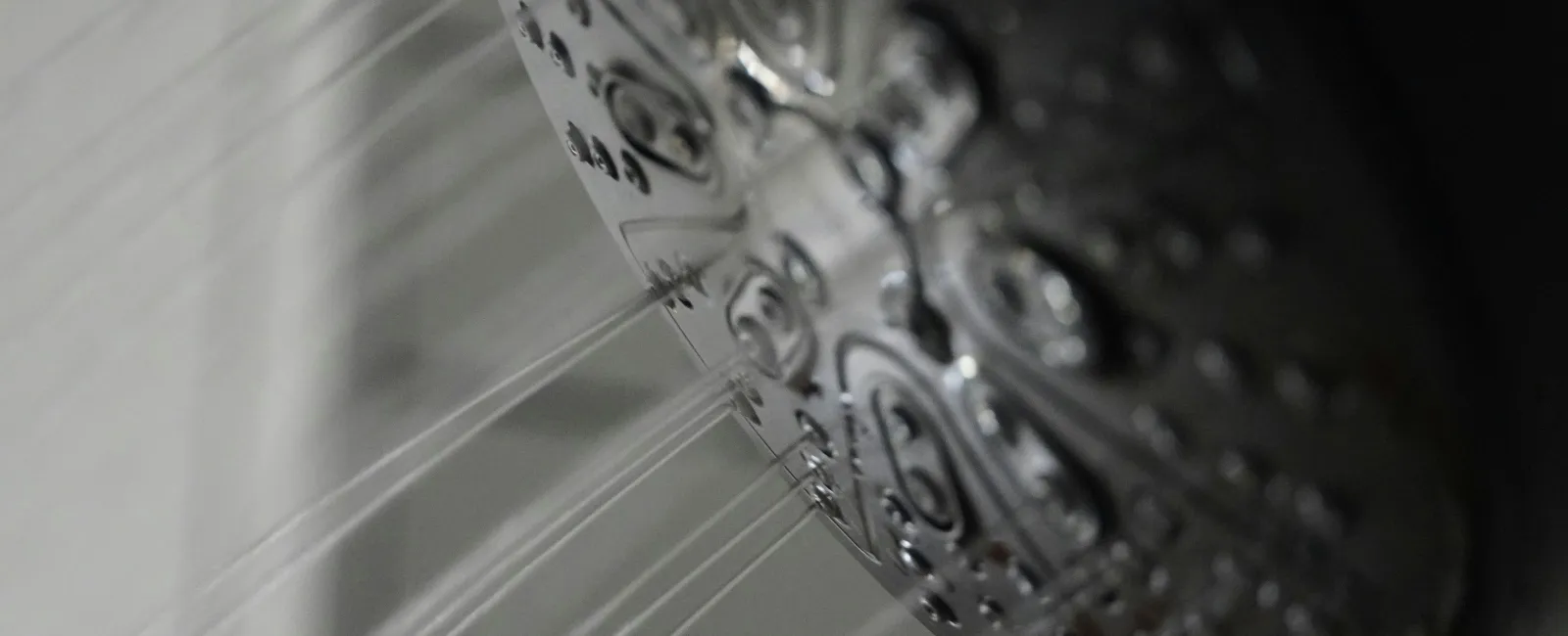 Close-up of a shower head spraying multiple streams of water in a bathroom setting.