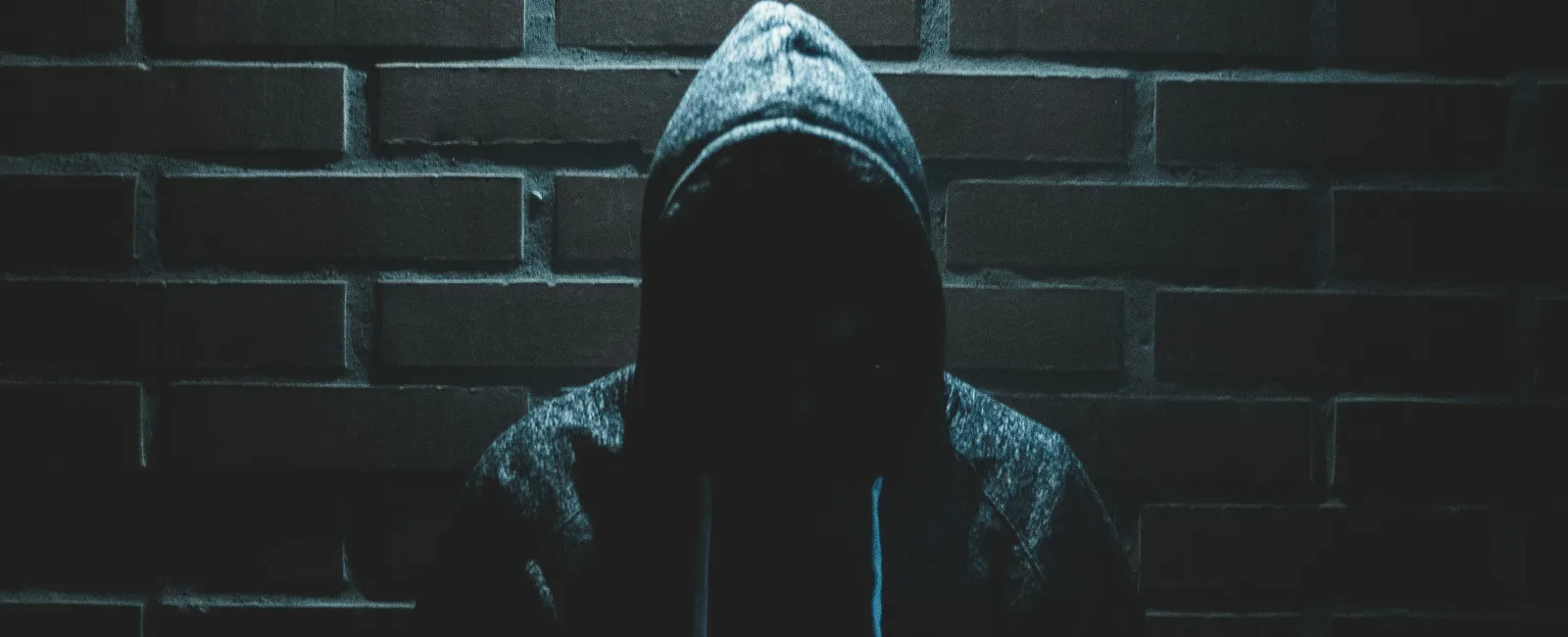 a person wearing a hoodie and a hat in a dark room