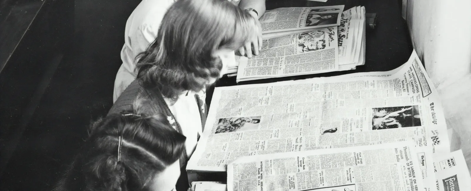 a group of women looking at a newspaper