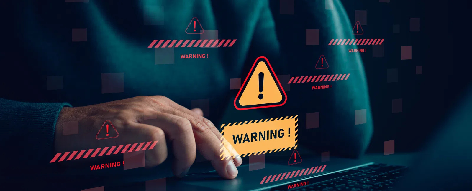 Person using laptop with digital warning alerts and caution signs displayed above keyboard in low light.
