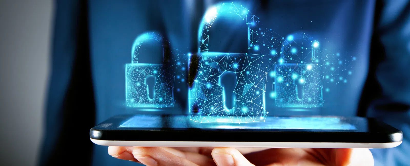 Businessman holding a tablet with digital holographic padlocks symbolizing cybersecurity and data protection.