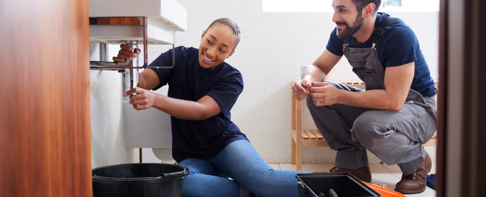 a man and a woman sitting on the floor with a bucket and a bucket of paint