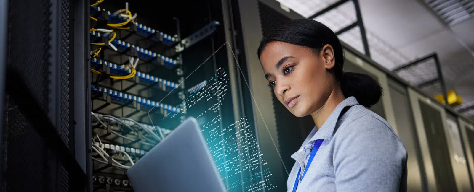 IT professional working on a laptop in a server room with digital data overlay and network infrastructure.