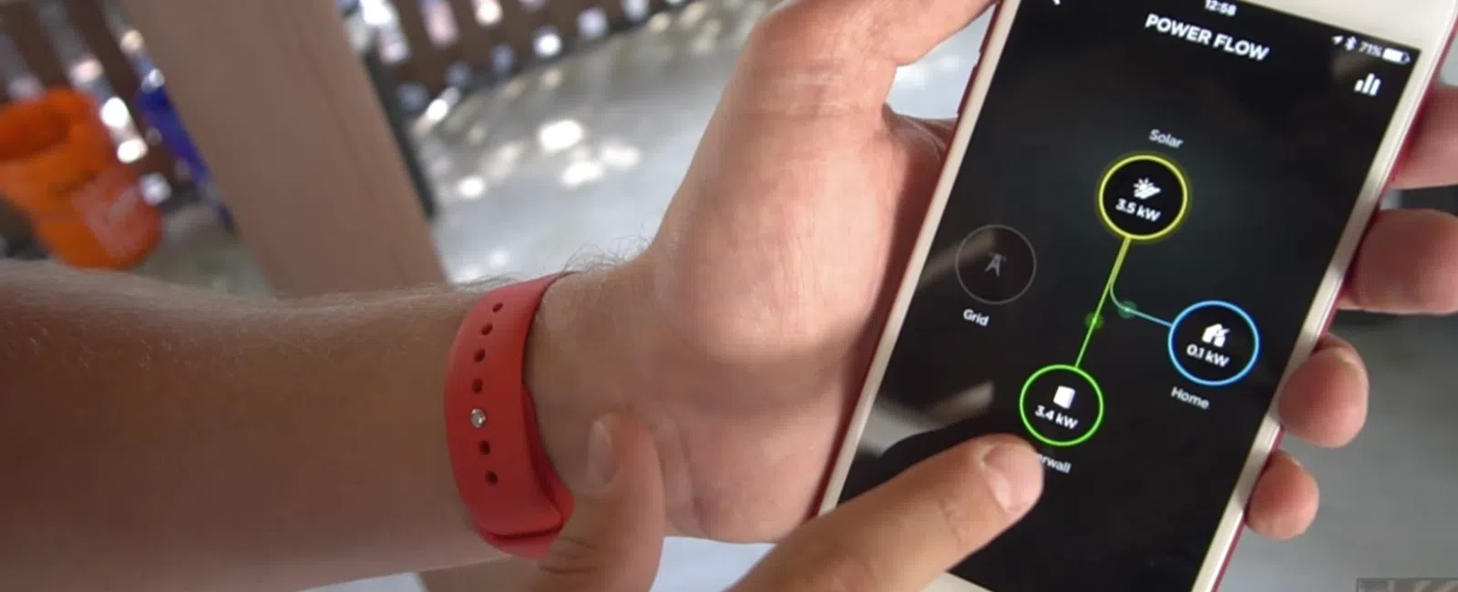 Person using smartphone app to monitor solar power flow and energy consumption at home.