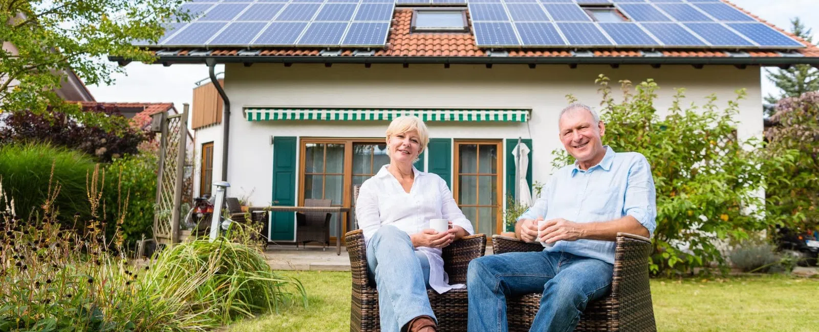 Happy couple enjoying their garden with a solar panel-equipped house in the background.