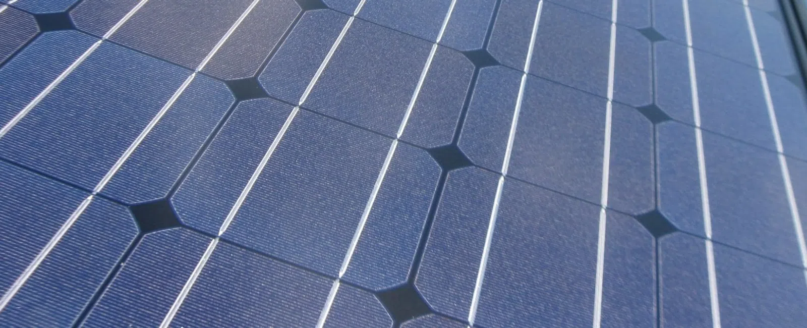 Close-up view of blue solar panels with white grid lines, showcasing renewable energy technology.