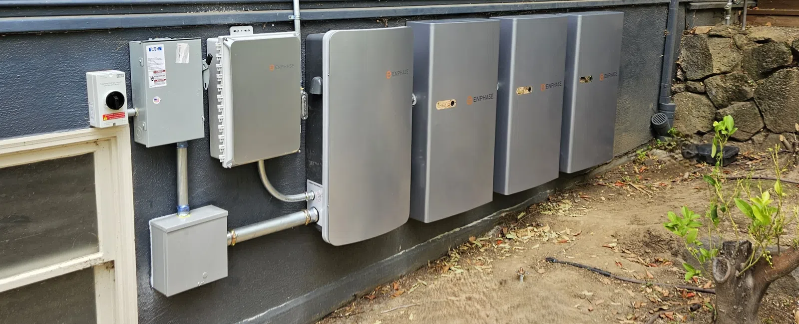 Row of solar battery storage units mounted on a house exterior, promoting sustainable energy solutions.