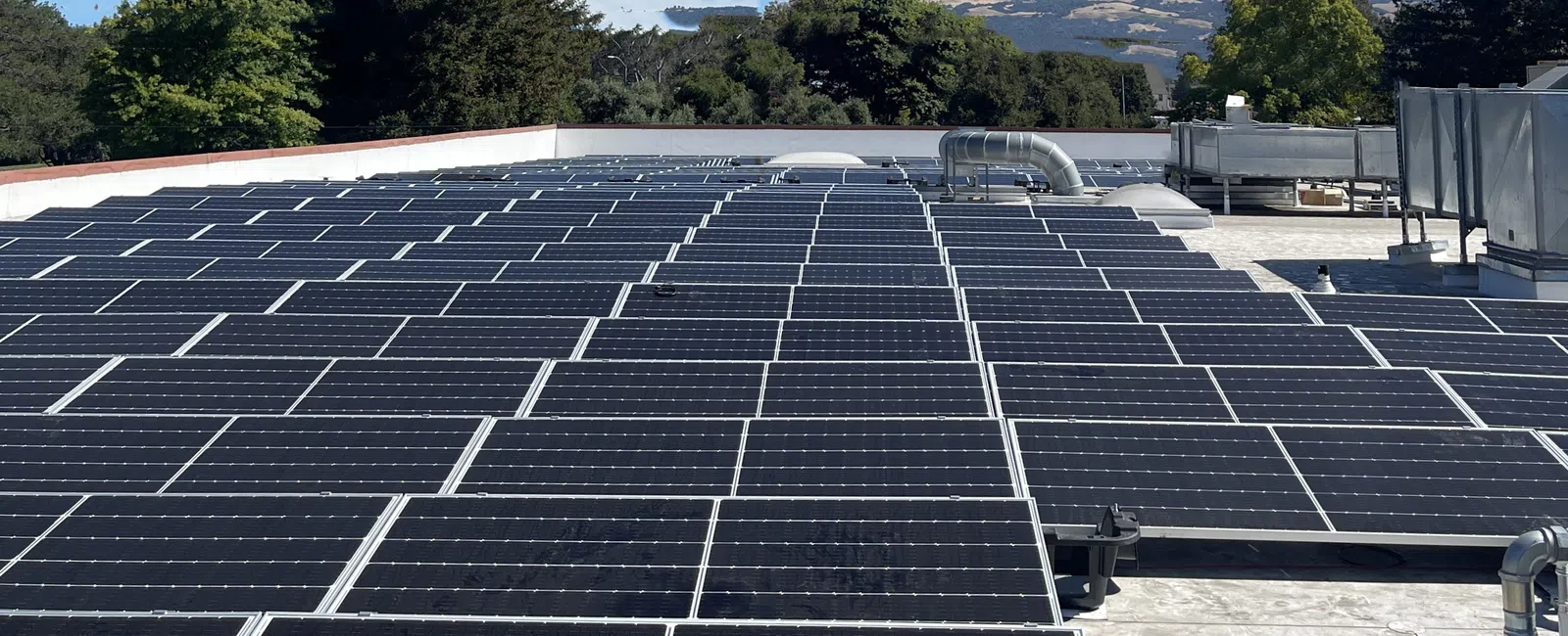 A rooftop covered with solar panels under a clear blue sky, showcasing renewable energy solutions.