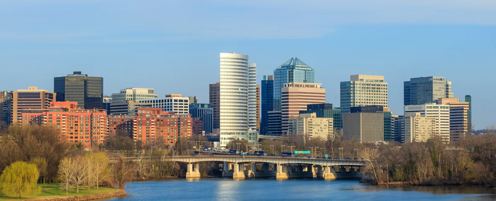 Skyline of Arlington Virginia with Potomac River and Key Bridge in clear daylight under blue sky.