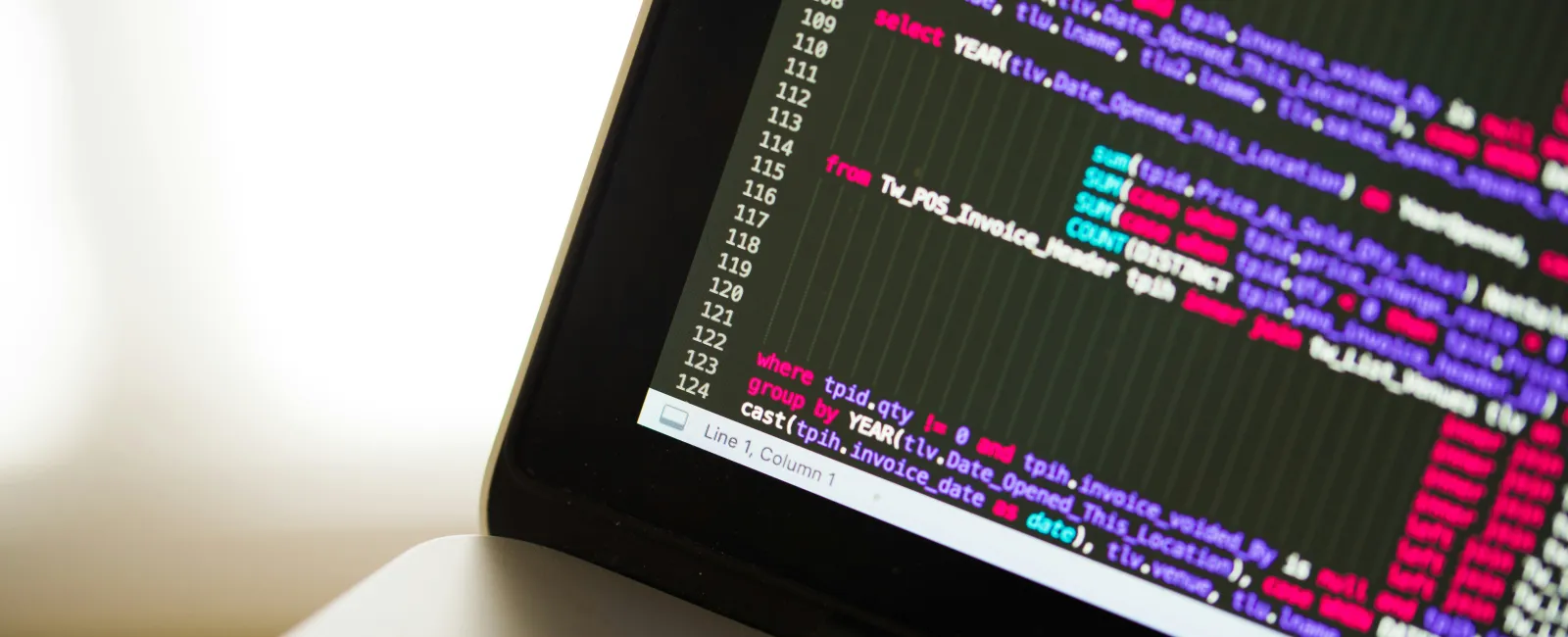 Close-up of laptop screen displaying colorful lines of computer code representing the threat of cyberattacks.