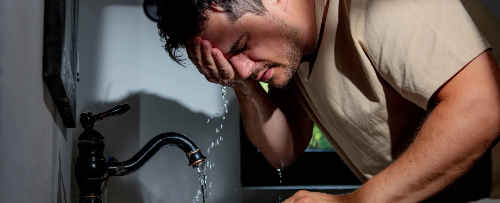 a man sitting in front of a sink with his head in his hand