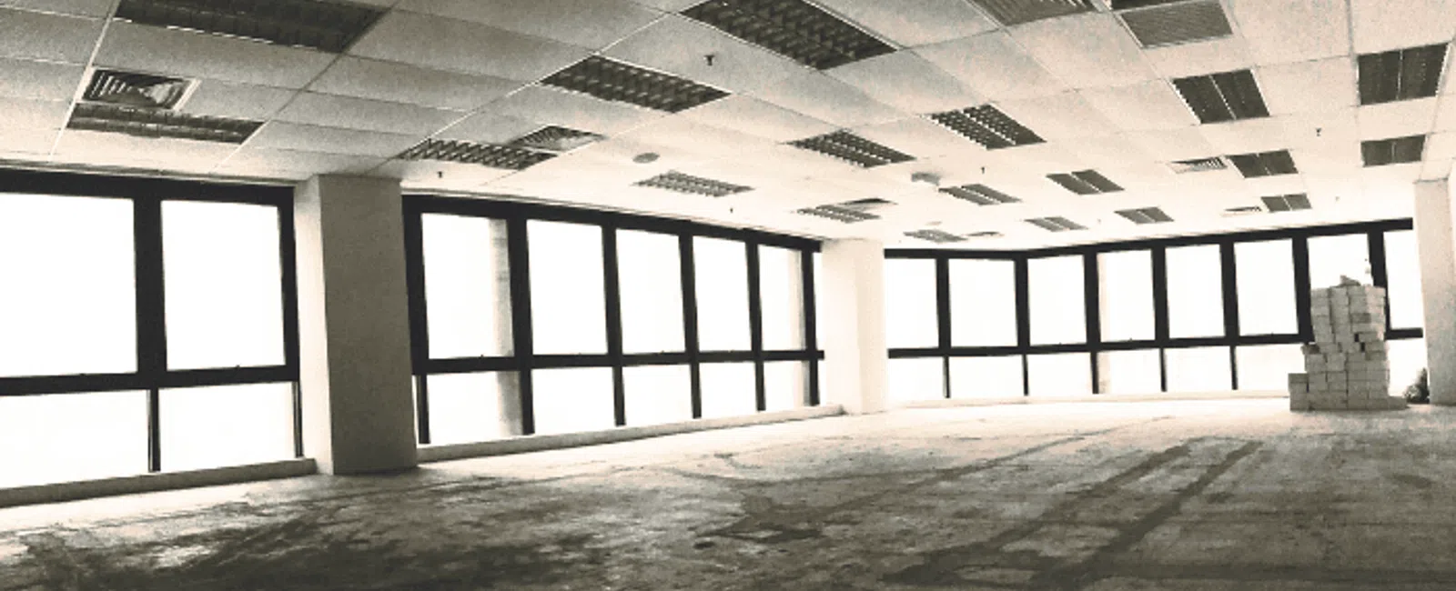 Empty spacious office interior with large windows and tiled ceiling ready for renovation or furnishing