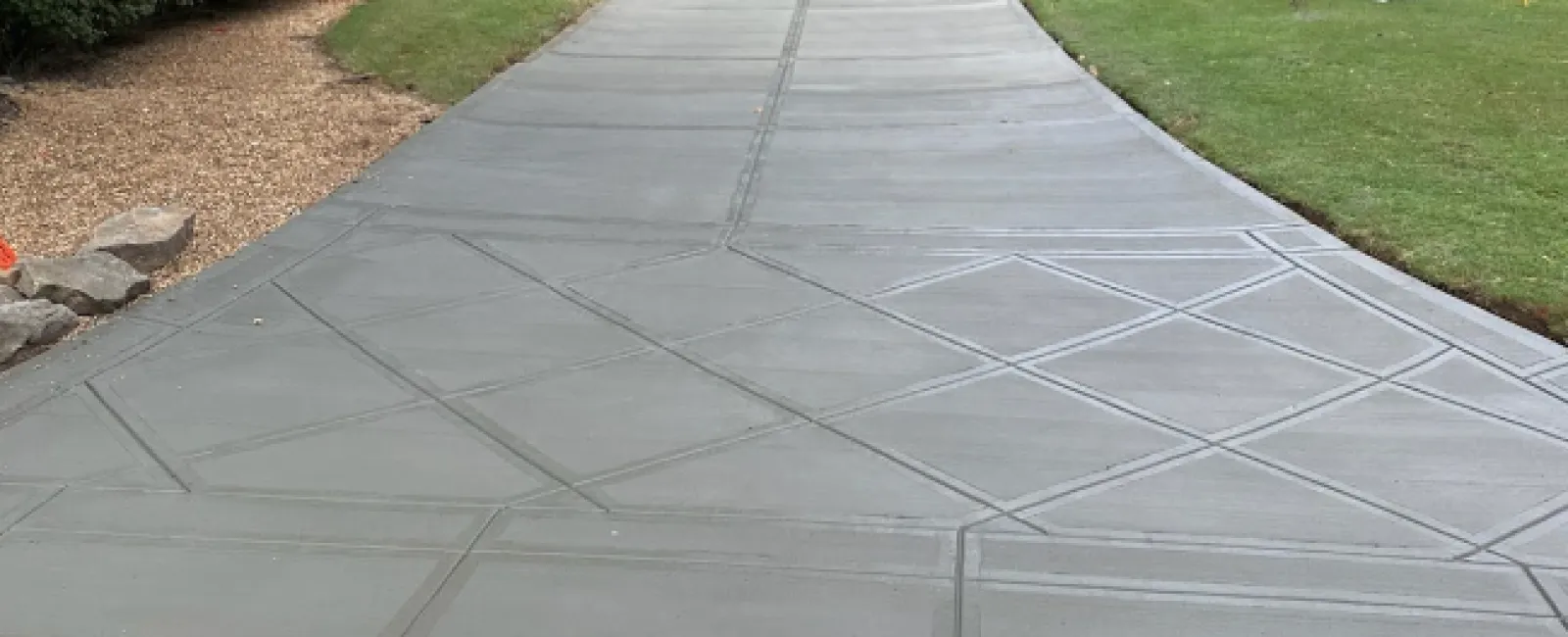 a paved walkway with grass and trees