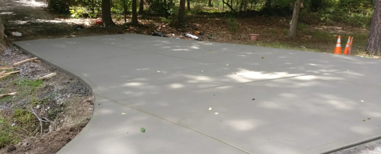 a concrete walkway with trees and a cone on the side