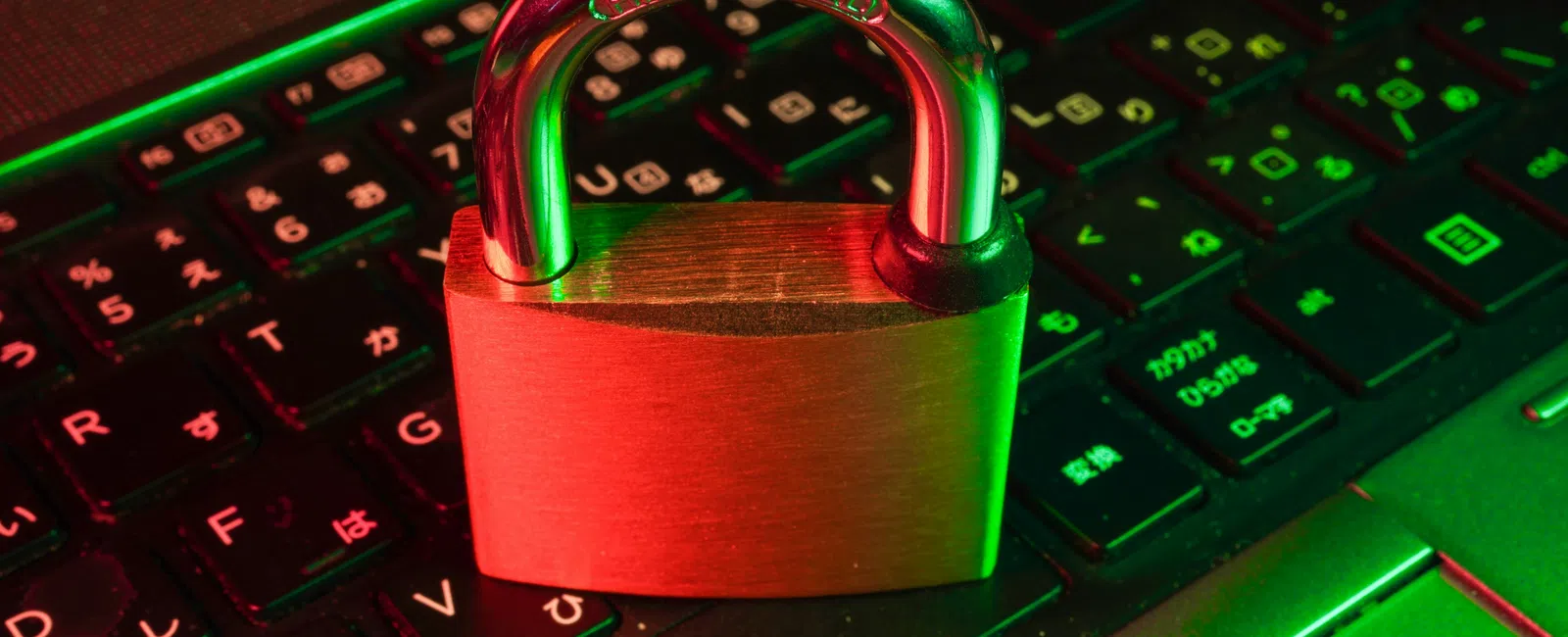 Padlock on a laptop keyboard symbolizing cybersecurity and data protection with green and red lighting.