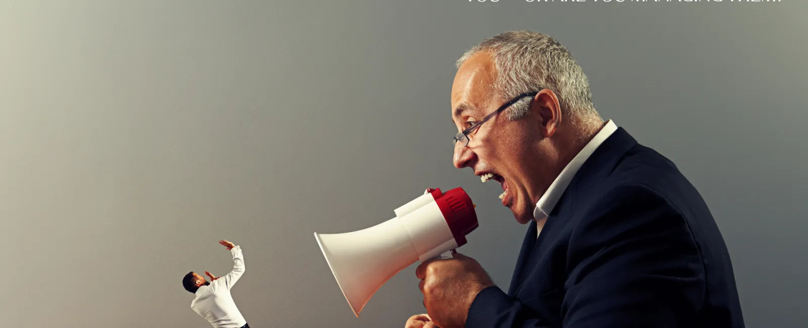 Giant man with megaphone shouting at a scared smaller man against a plain wall background.