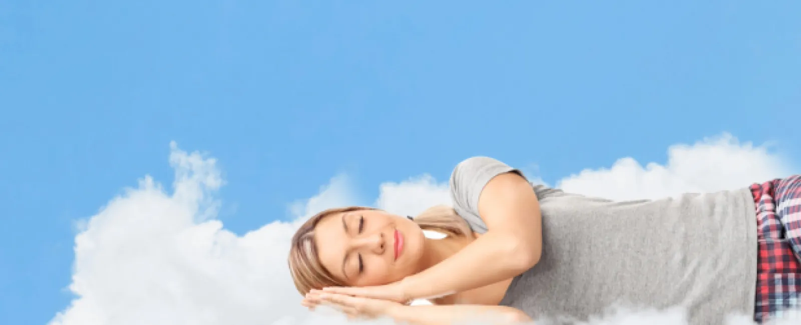 Woman peacefully sleeping on soft white clouds against a bright blue sky with scattered clouds.