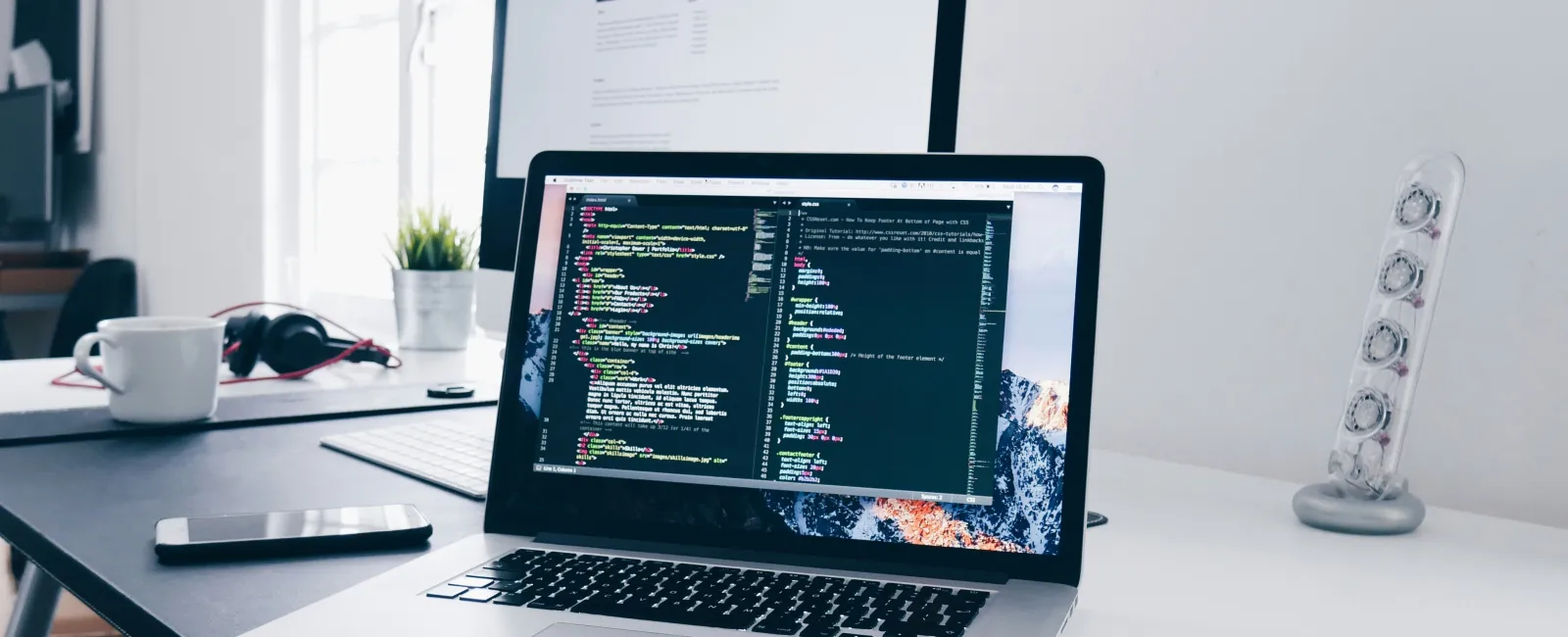 Laptop on a desk displaying code editor with programming code, surrounded by office items showcasing local IT management