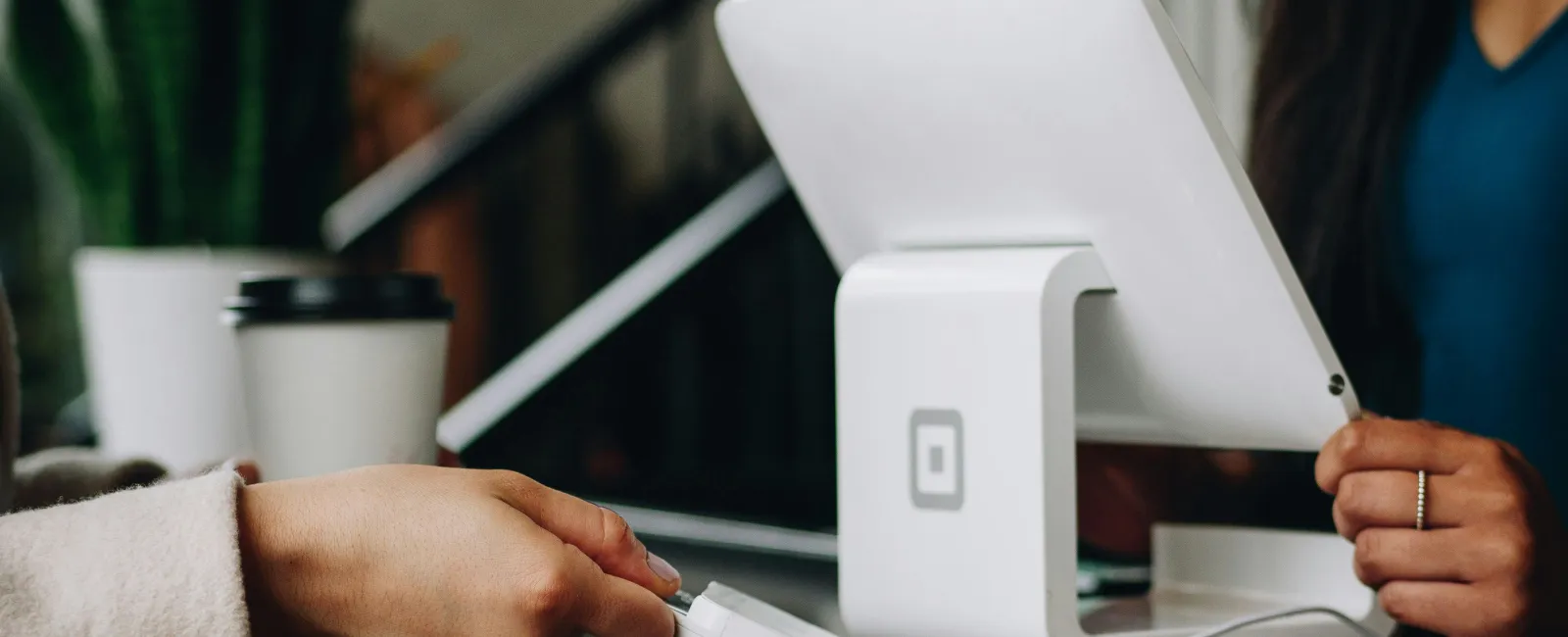 Person making a payment using a card reader at a small business modern white point-of-sale terminal showing that small businesses need cybersecurity.