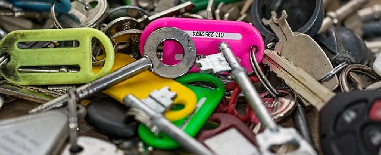 Close-up of assorted keys and colorful plastic key tags on a messy surface