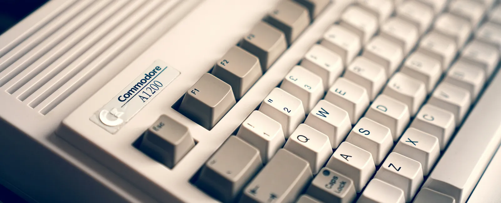 Close-up of a vClose-up of a vintage beige Commodore A1200 keyboard showcasing that old tech can cost small businesses money.intage beige Commodore A1Close-up of a vintage beige Commodore A1200 keyboard showcasing that old tech can cost small businesses money.200 retro computer keyboard with labeled keys.