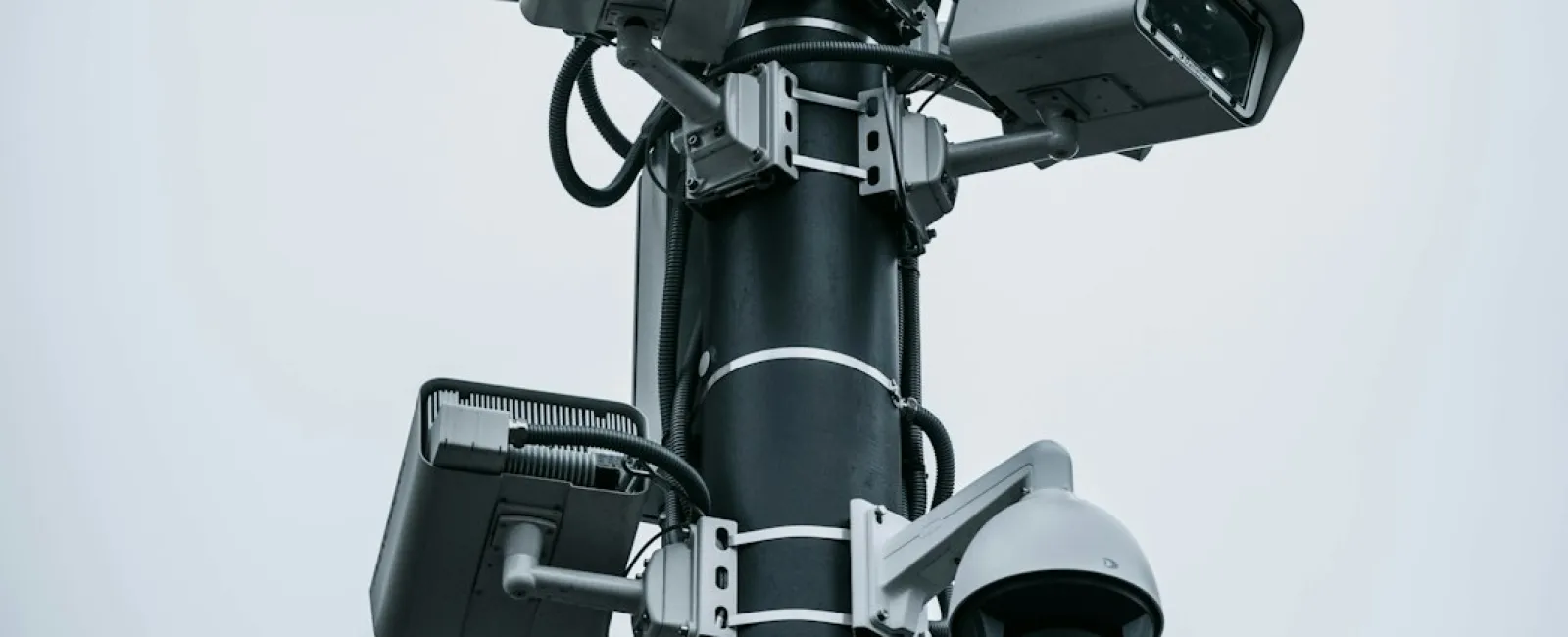 Multiple Panomera security cameras mounted on a tall black pole against a gray sky.