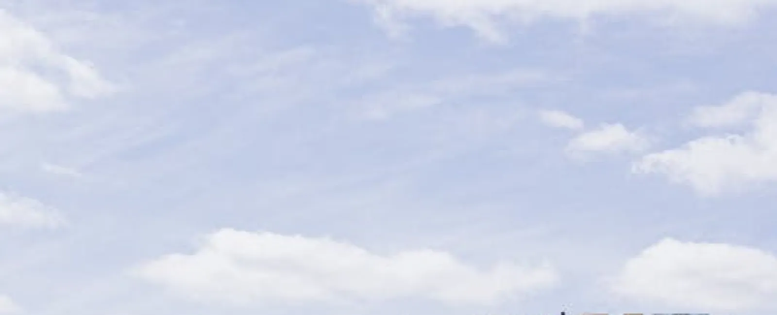 Three modern high-rise buildings under a partly cloudy sky with reflective glass windows and geometric design.