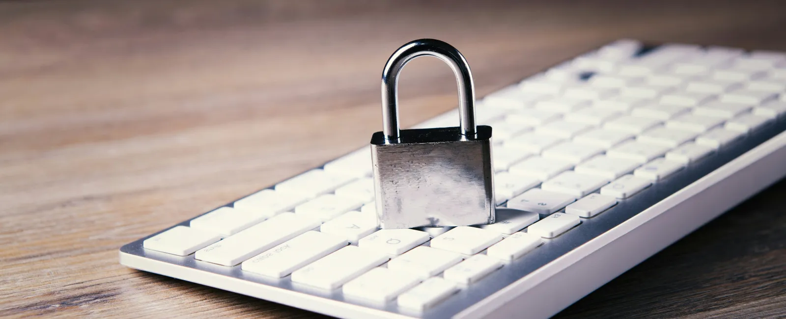 Silver padlock placed on a white computer keyboard symbolizing cybersecurity and cyber insurance.