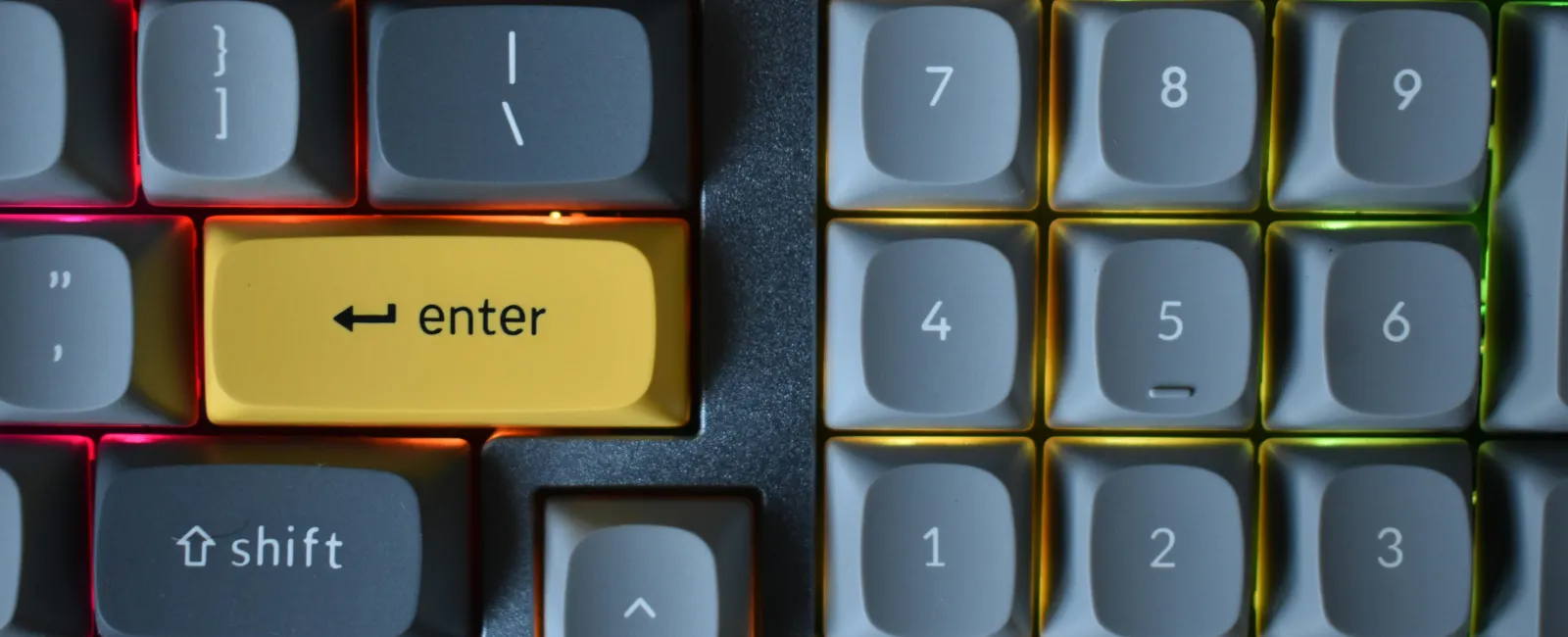 Close-up of a computer keyboard with a yellow Enter key and illuminated numeric keypad key - unlock managed it solutions
