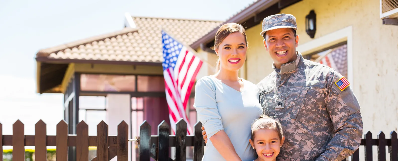 a family standing in front of a fence and a flag
