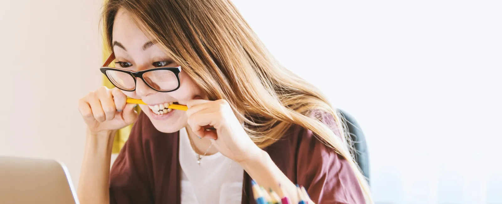 a woman with glasses and a pencil in her mouth