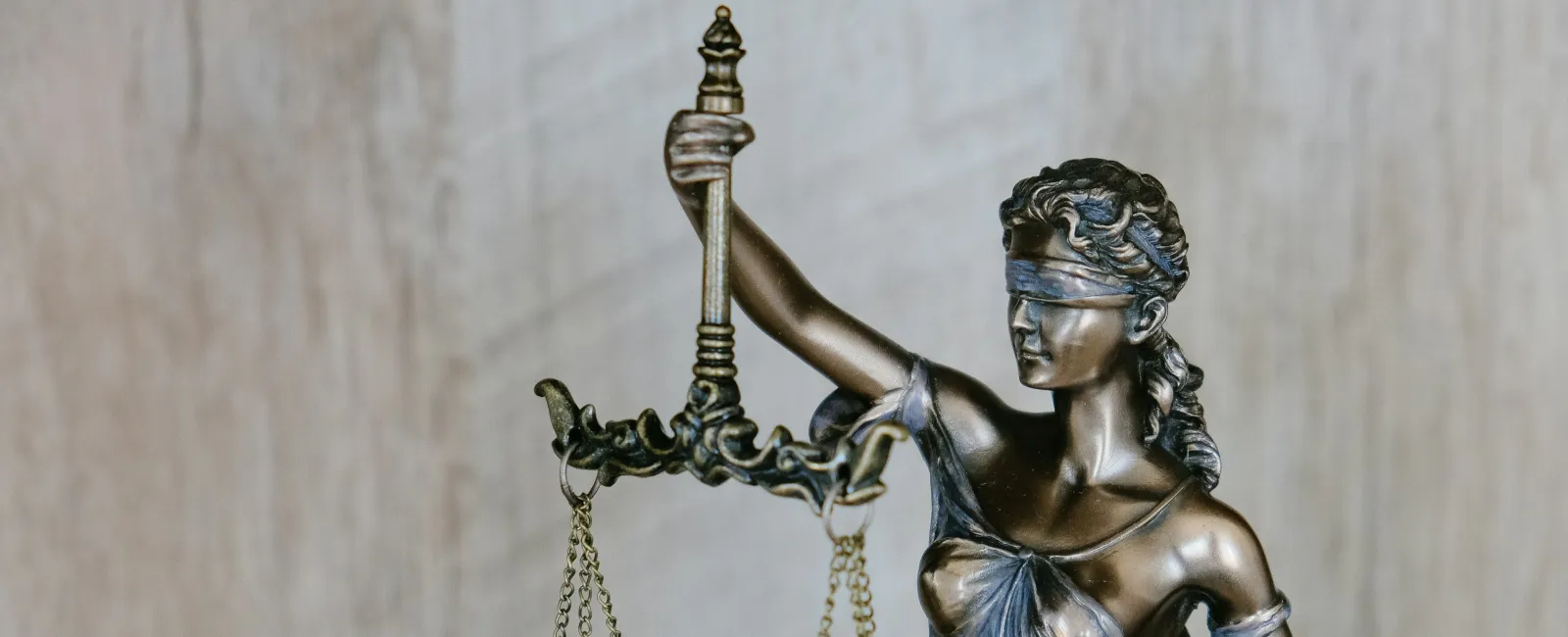 Bronze statue of blindfolded Lady Justice holding balanced scales symbolizing fairness and law