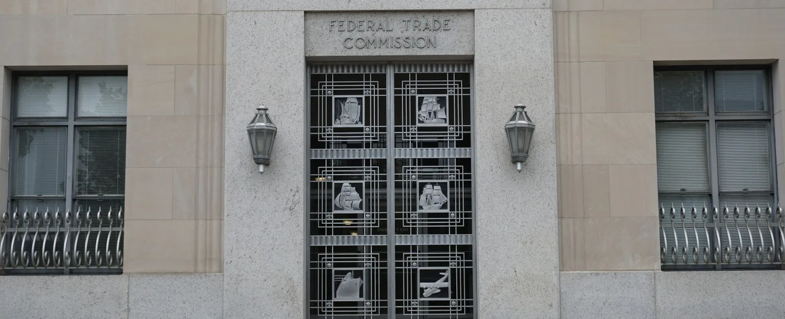 Entrance of the Federal Trade Commission building featuring decorative metal doors and stone facade.